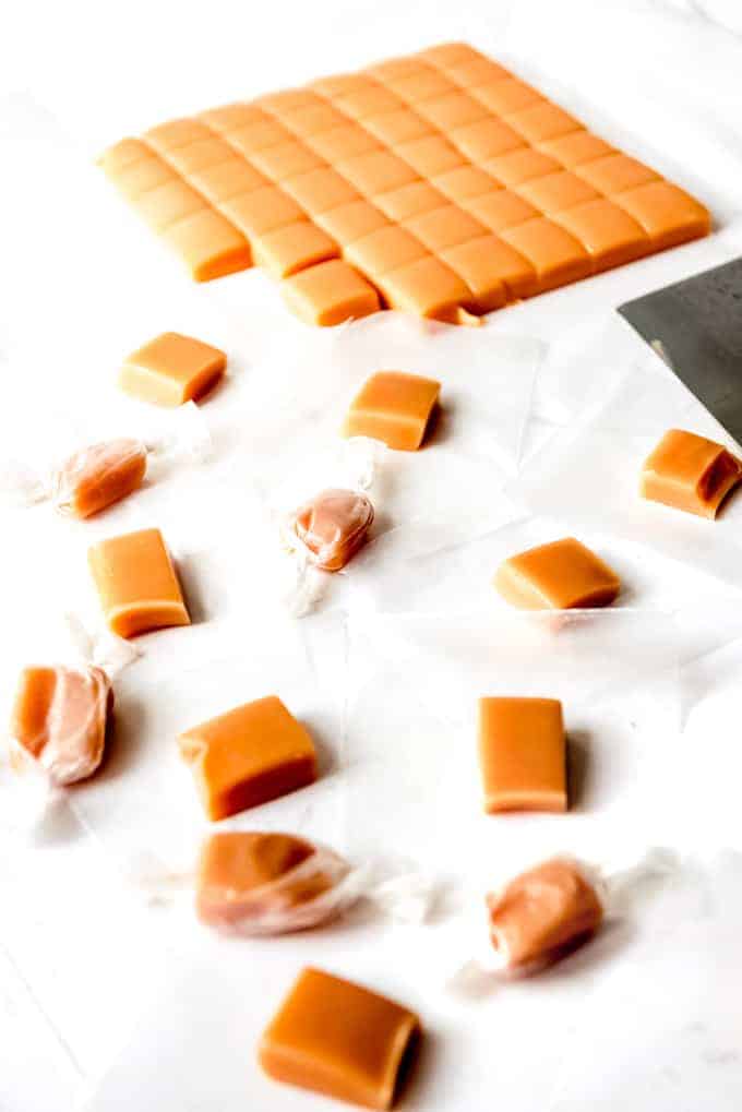 An image of homemade caramels being cut and wrapped in waxed paper.
