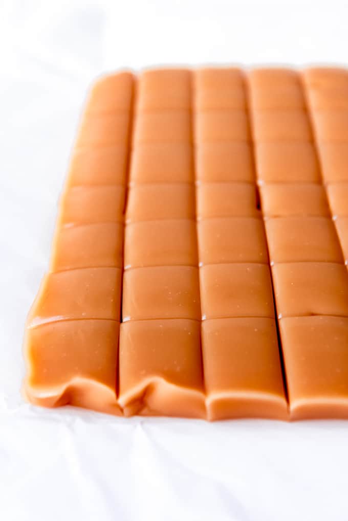 An image of a bar of caramel being sliced into squares.