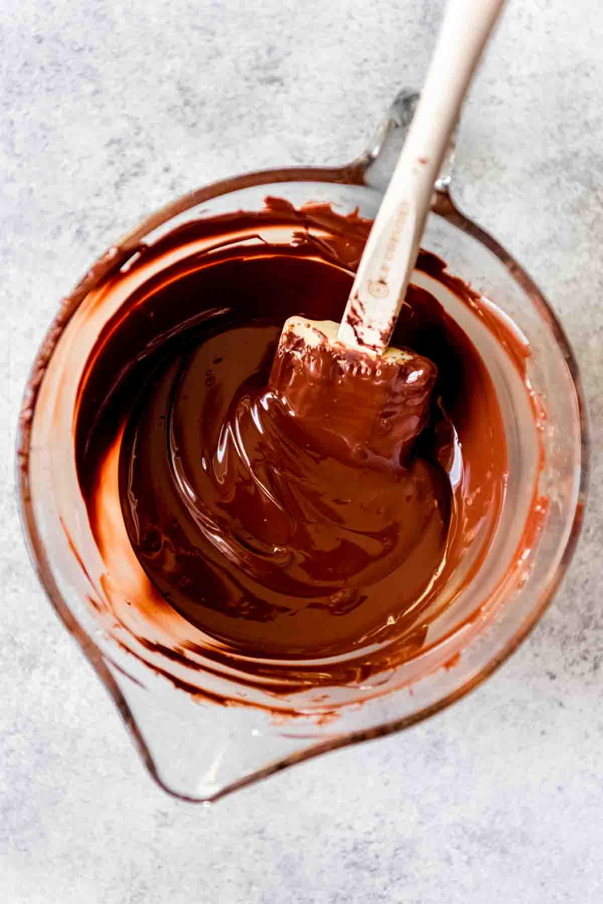 Melted dark chocolate in a bowl with a spatula.