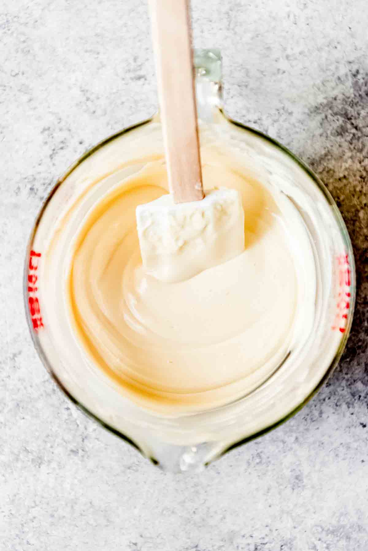 Melted white chocolate in a bowl with a spatula.