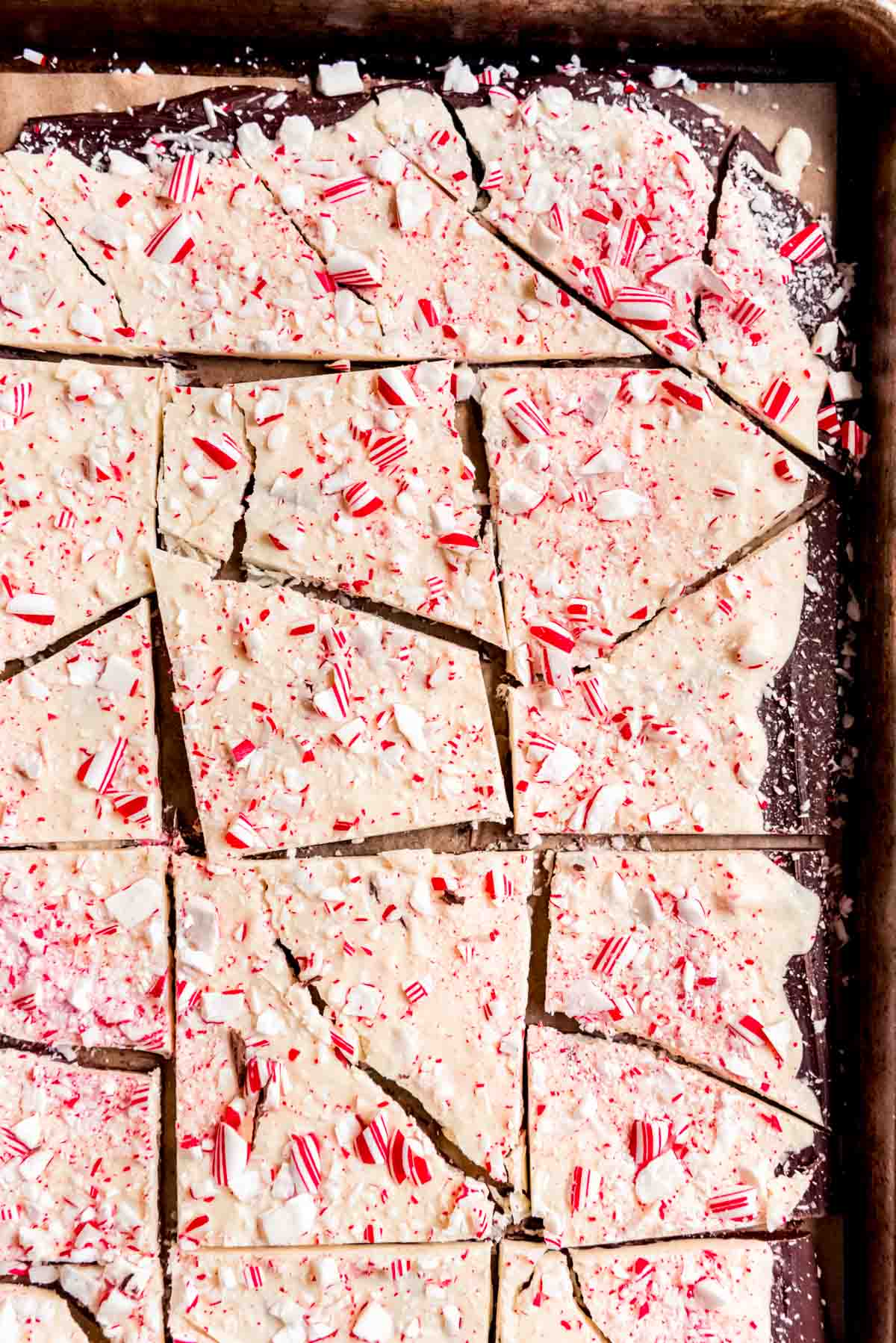 An image of broken up chunks of peppermint bark on a baking sheet.