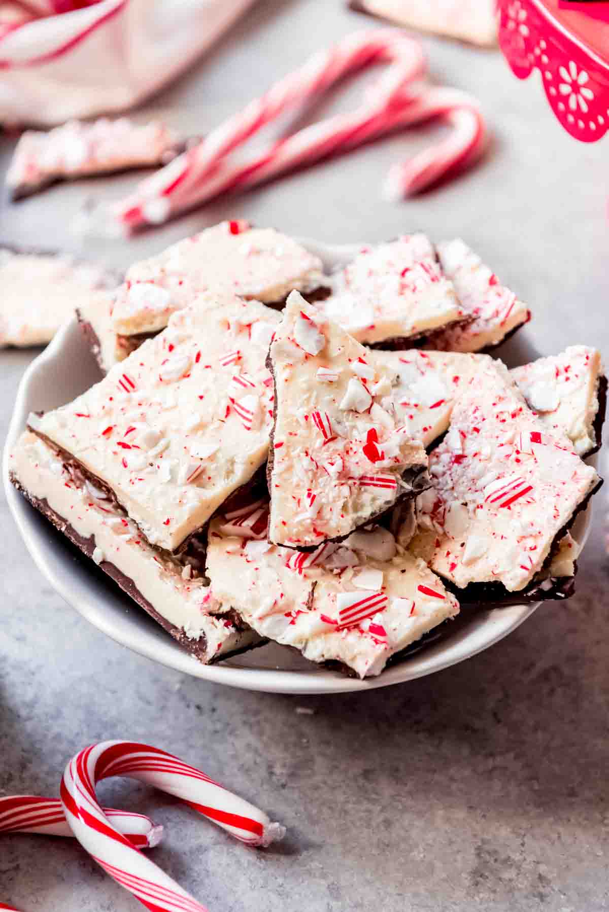 An image of pieces of homemade peppermint bark in a bowl next to some candy canes.