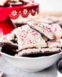 An image of pieces of homemade peppermint bark in a bowl next to some candy canes.