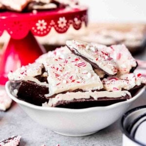 An image of pieces of homemade peppermint bark in a bowl next to some candy canes.