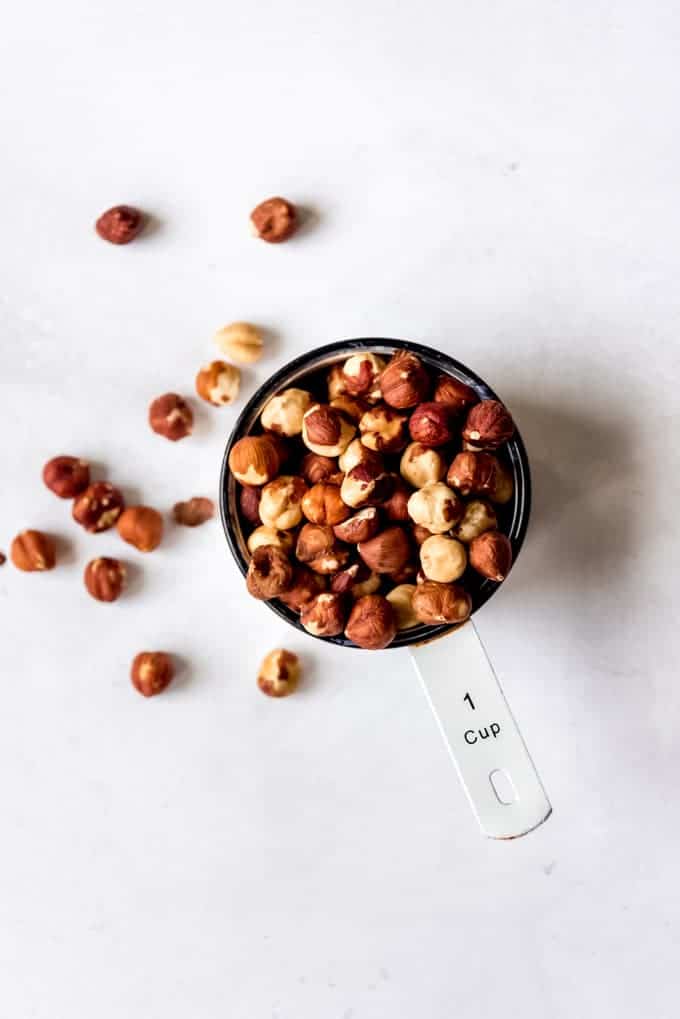 An image of whole hazelnuts in a measuring cup.