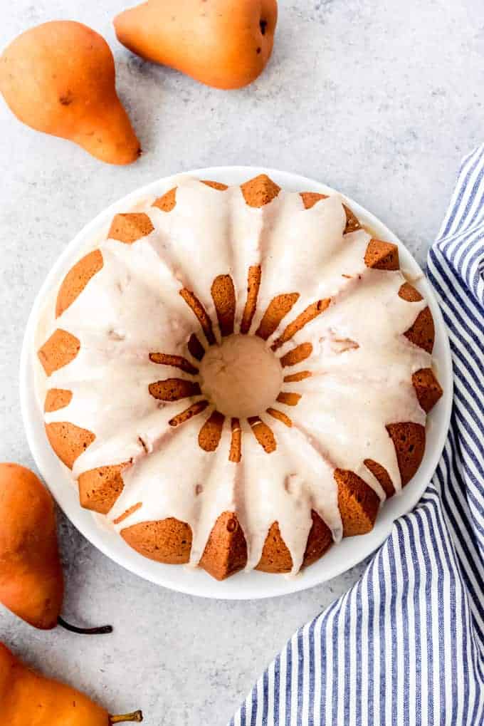 An image looking down on a glazed bundt cake surrounded by bosc pears.