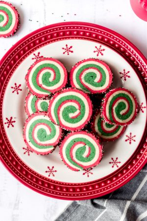 An image of Christmas pinwheel cookies on a festive red and white holiday plate.