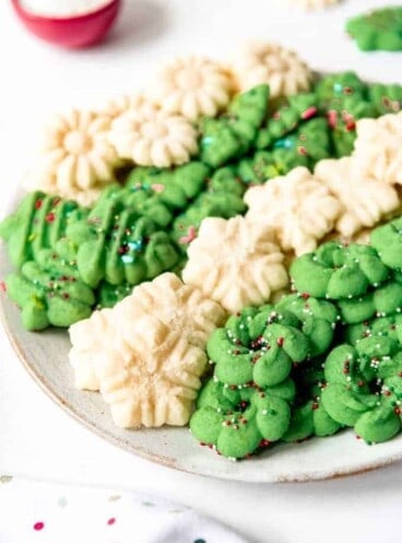 An image of classic Spritz cookies piled on a plate together.