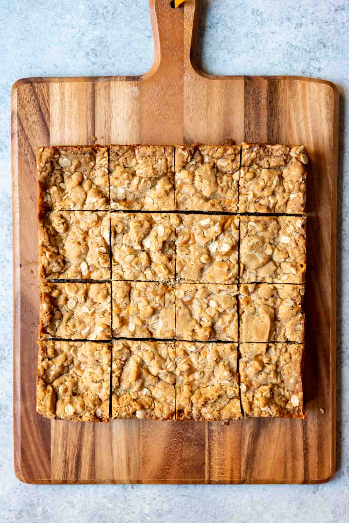 An image of carmelita bars that have been cut into squares on a wooden cutting board.