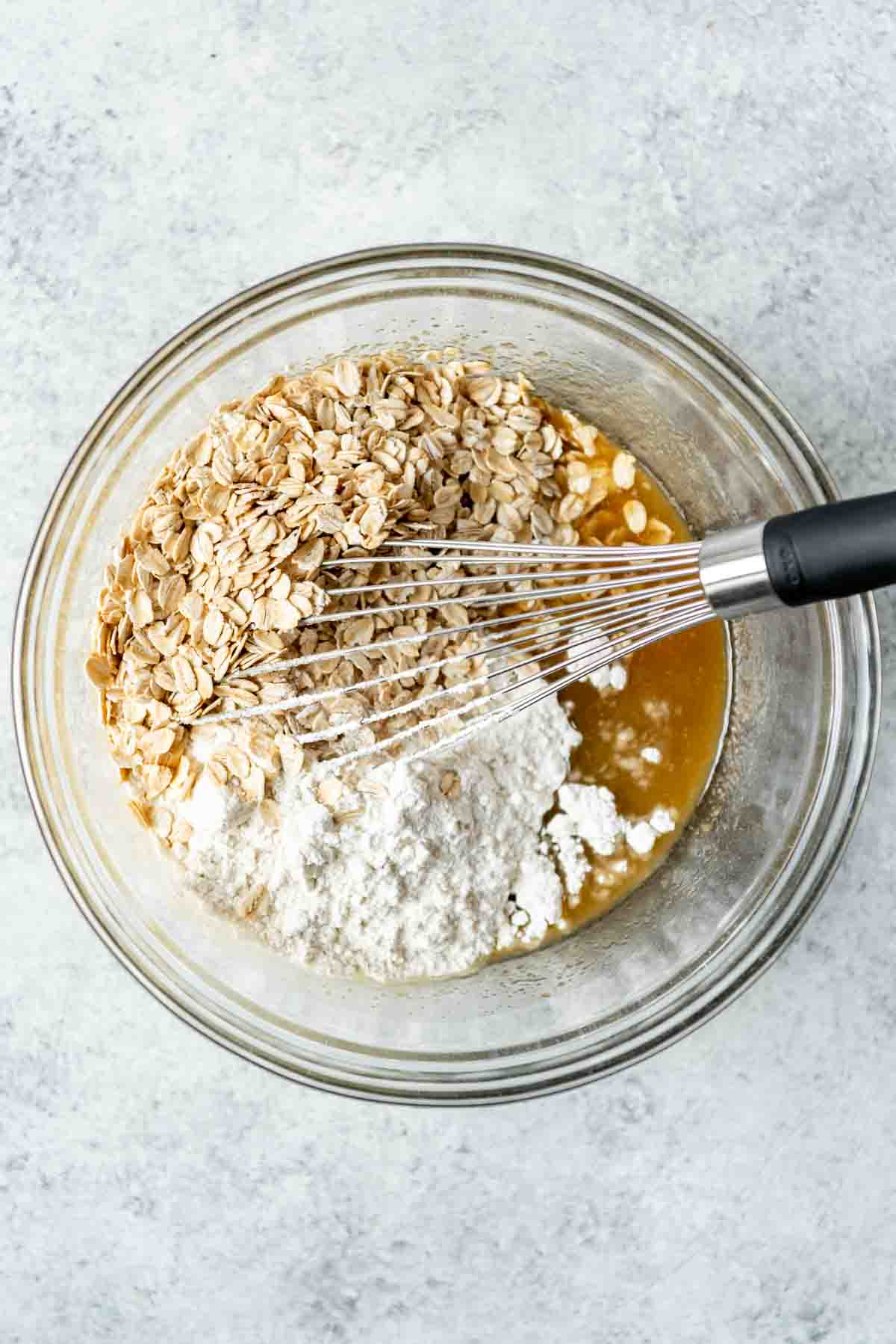 Adding oats and flour in a mixing bowl.