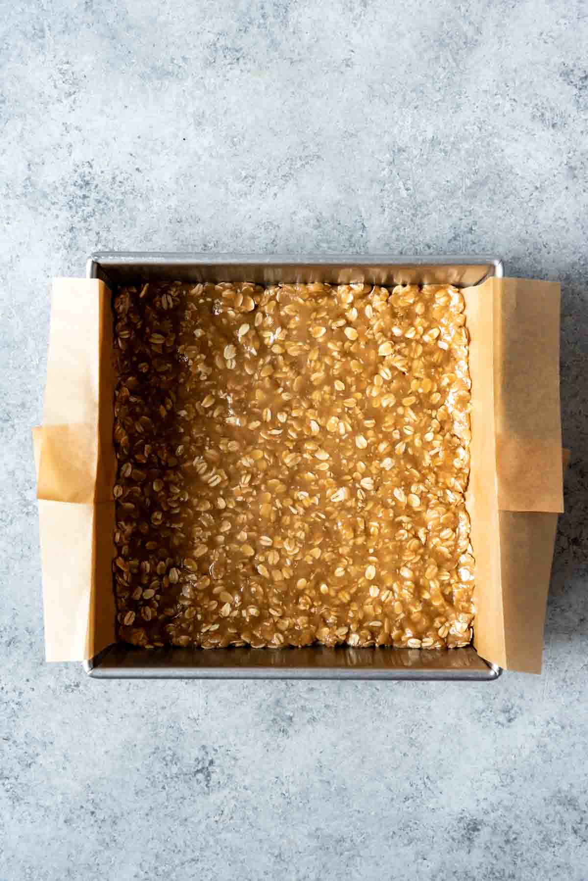 Pressing an oatmeal crust into a square baking pan.