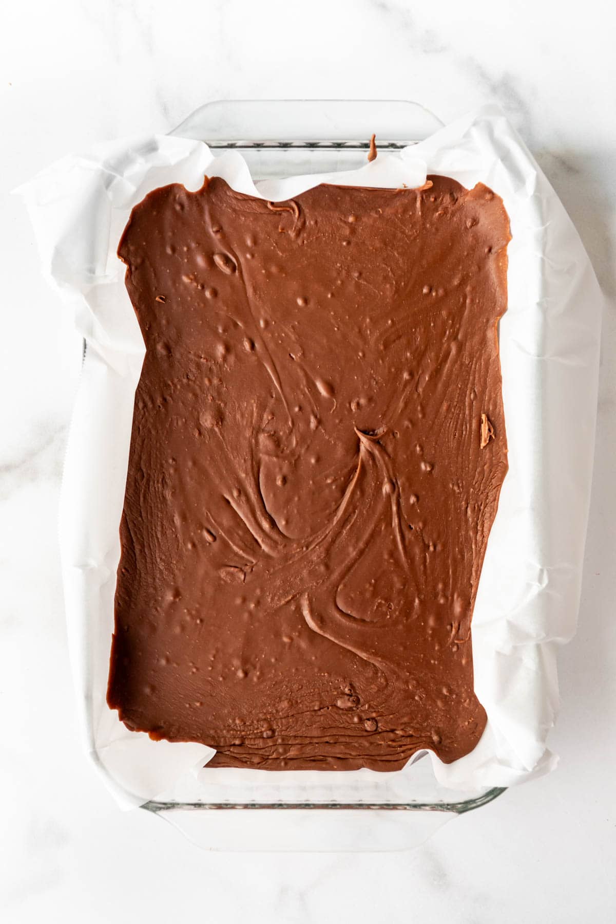 An image of chocolate fudge setting up in a 9x13-inch pan.