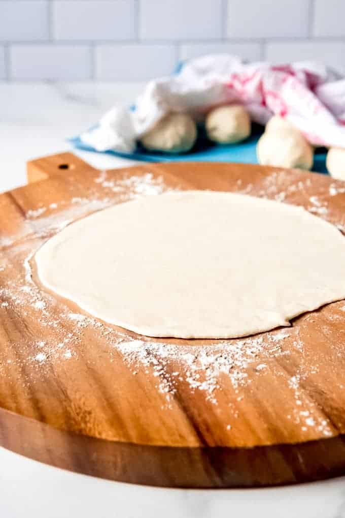 An image of tortilla dough that has been rolled out on a floured surface.