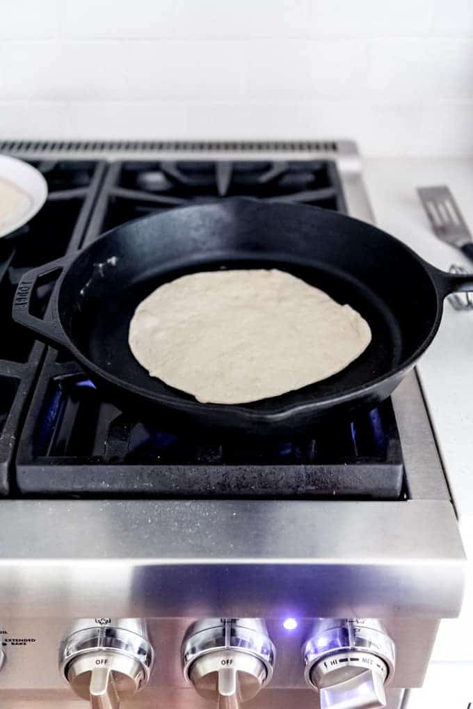 An image of a fresh tortilla cooking in a hot cast iron skillet.