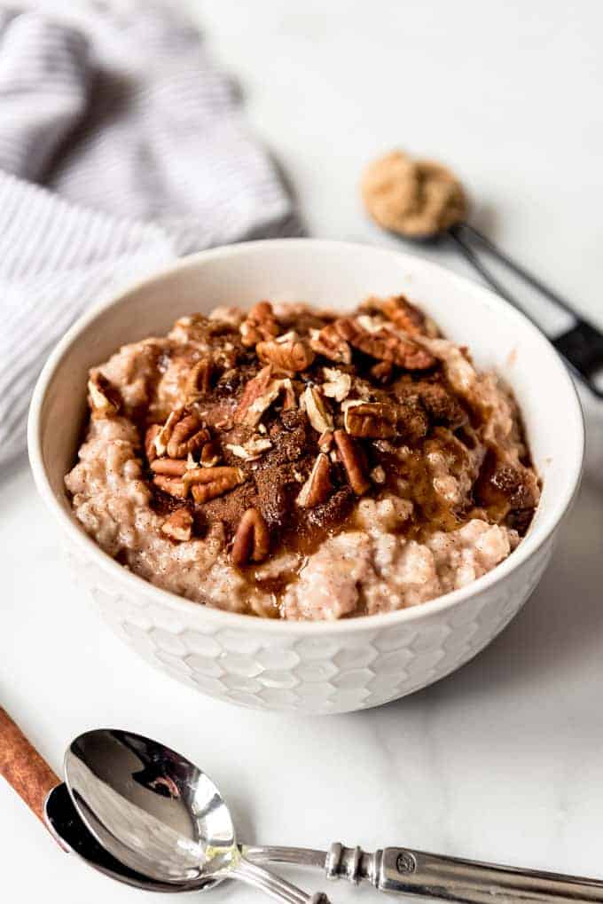 An image of a bowl of oatmeal topped with brown sugar, maple syrup, and pecans.