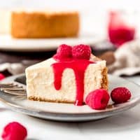 An image of a slice of Instant Pot Cheesecake topped with raspberry sauce.
