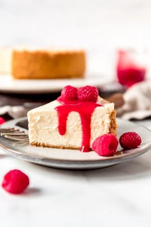An image of a slice of Instant Pot Cheesecake topped with raspberry sauce.