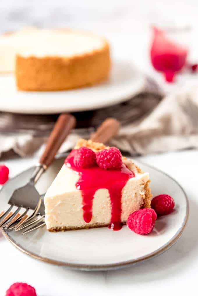 An image of a slice of classic New York cheesecake with raspberry sauce on top.