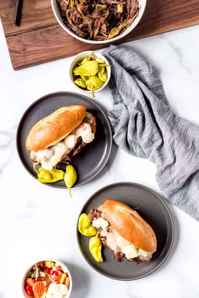 An image of roasted beef sandwiches with pepperoncinis and provolone cheese on hoagie buns.