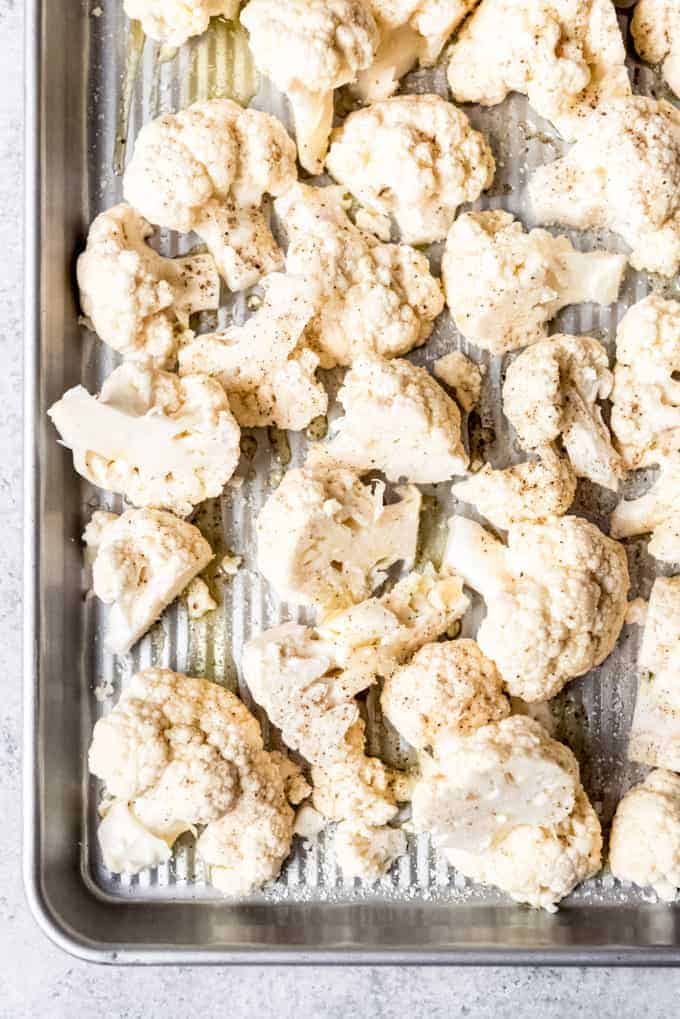An image of cauliflower florets drizzled with olive oil and seasoned with salt and pepper.