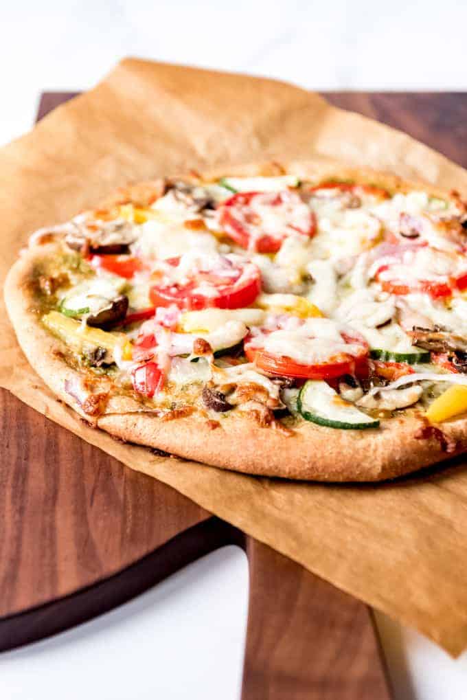 An image of a whole wheat pizza crust topped with roasted vegetables and cheese.