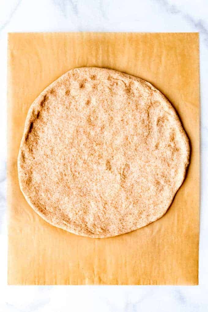 An image of whole wheat pizza dough stretched out into a circle.
