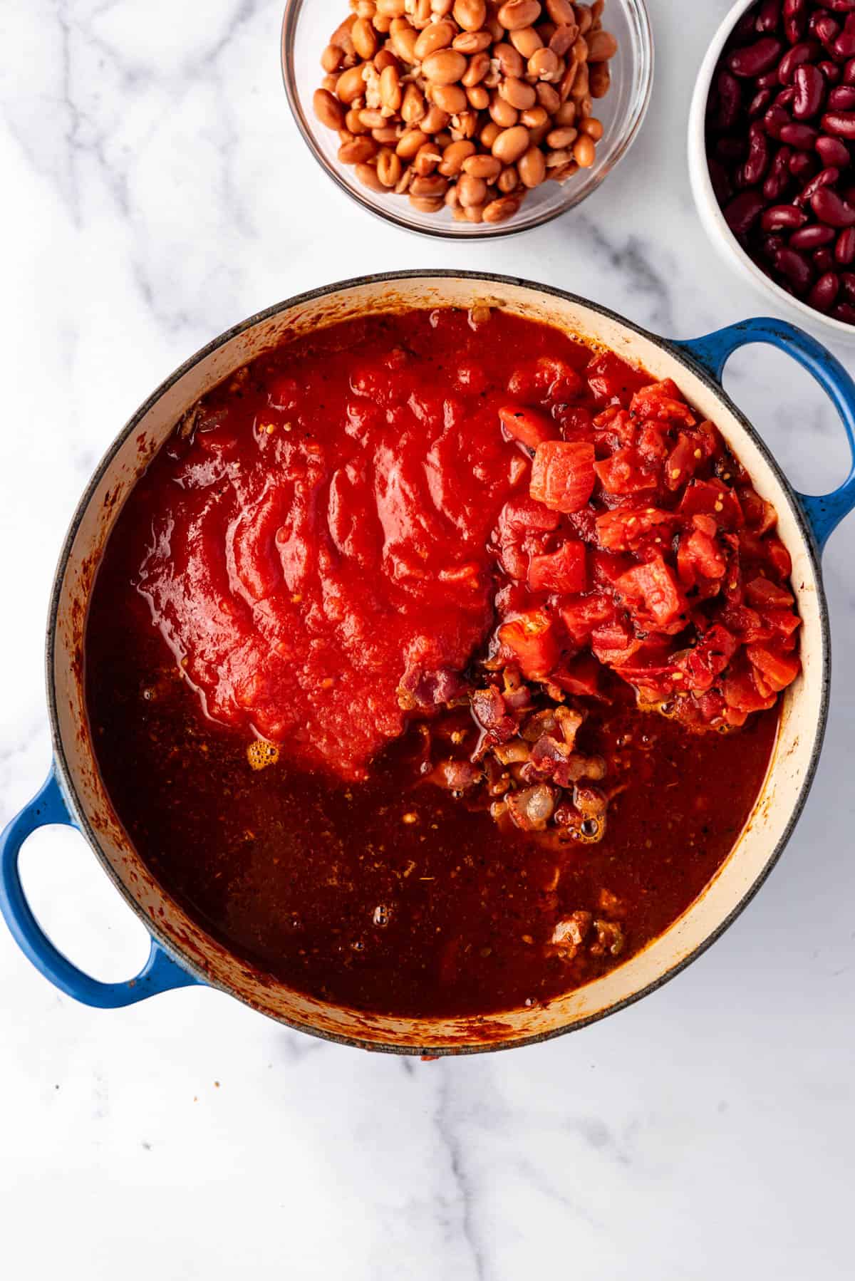 Adding tomato sauce to a pot of chili.