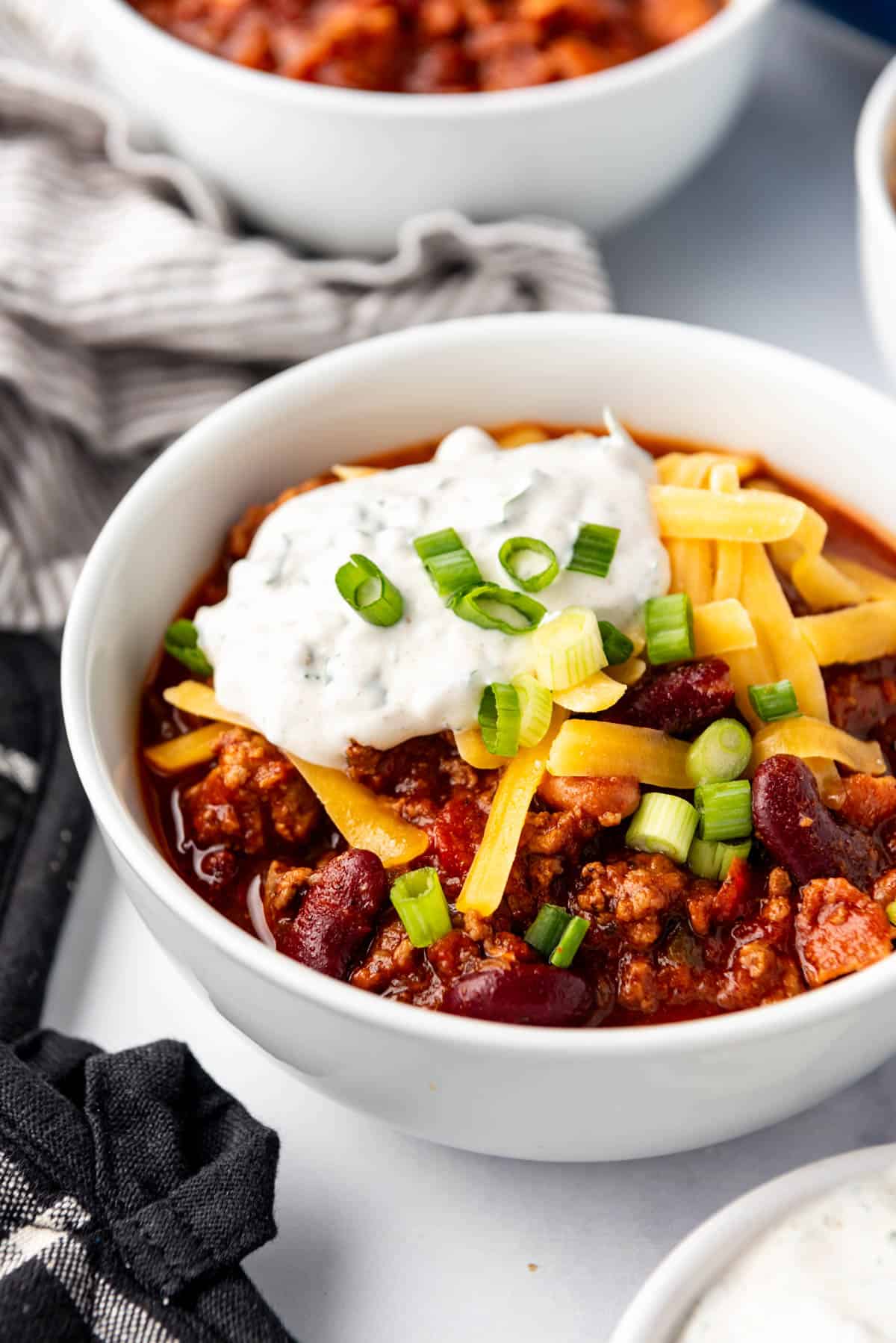 A bowl of chili with cheese and sour cream.