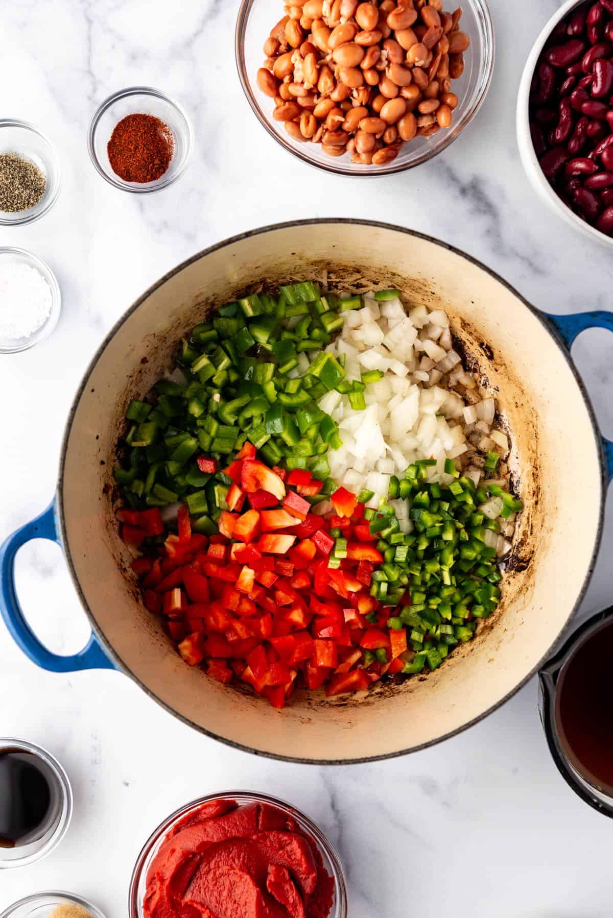 Adding diced veggies to bacon fat in a dutch oven. 