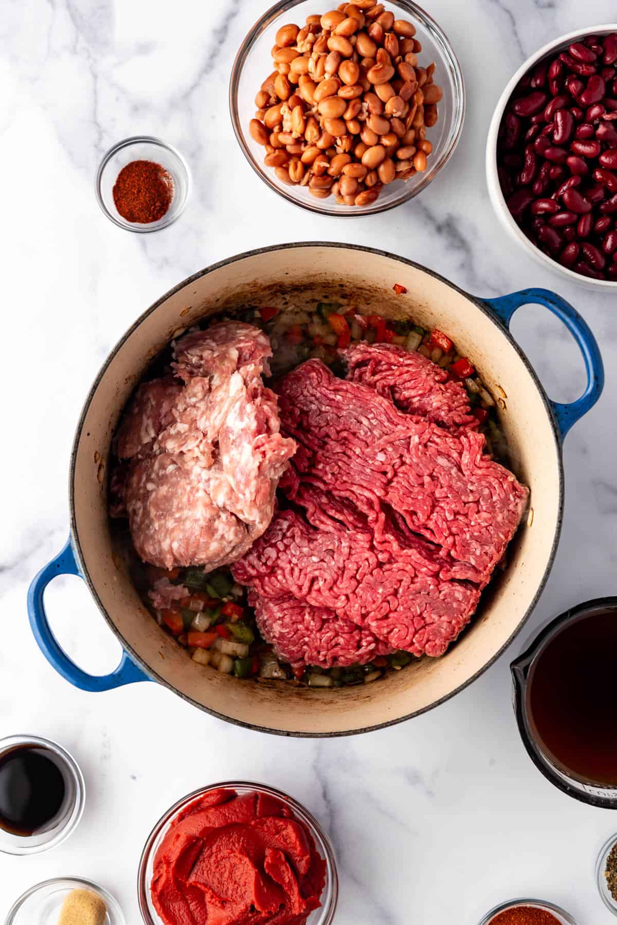 Adding ground beef and ground pork to a large dutch oven.