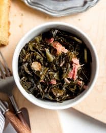 An image of a bowl of slow cooked greens with bits of smoky ham hock.