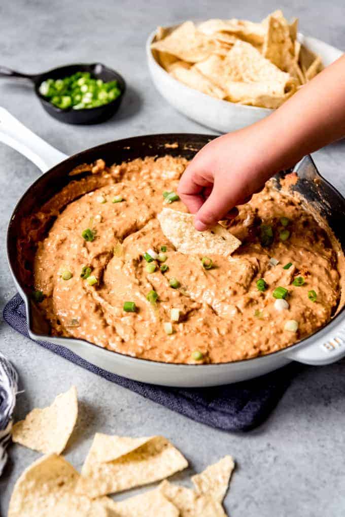 An image of a hand dipping a chip into an easy homemade bean dip.