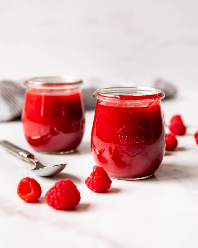 An image of two jars of homemade raspberry coulis sauce.