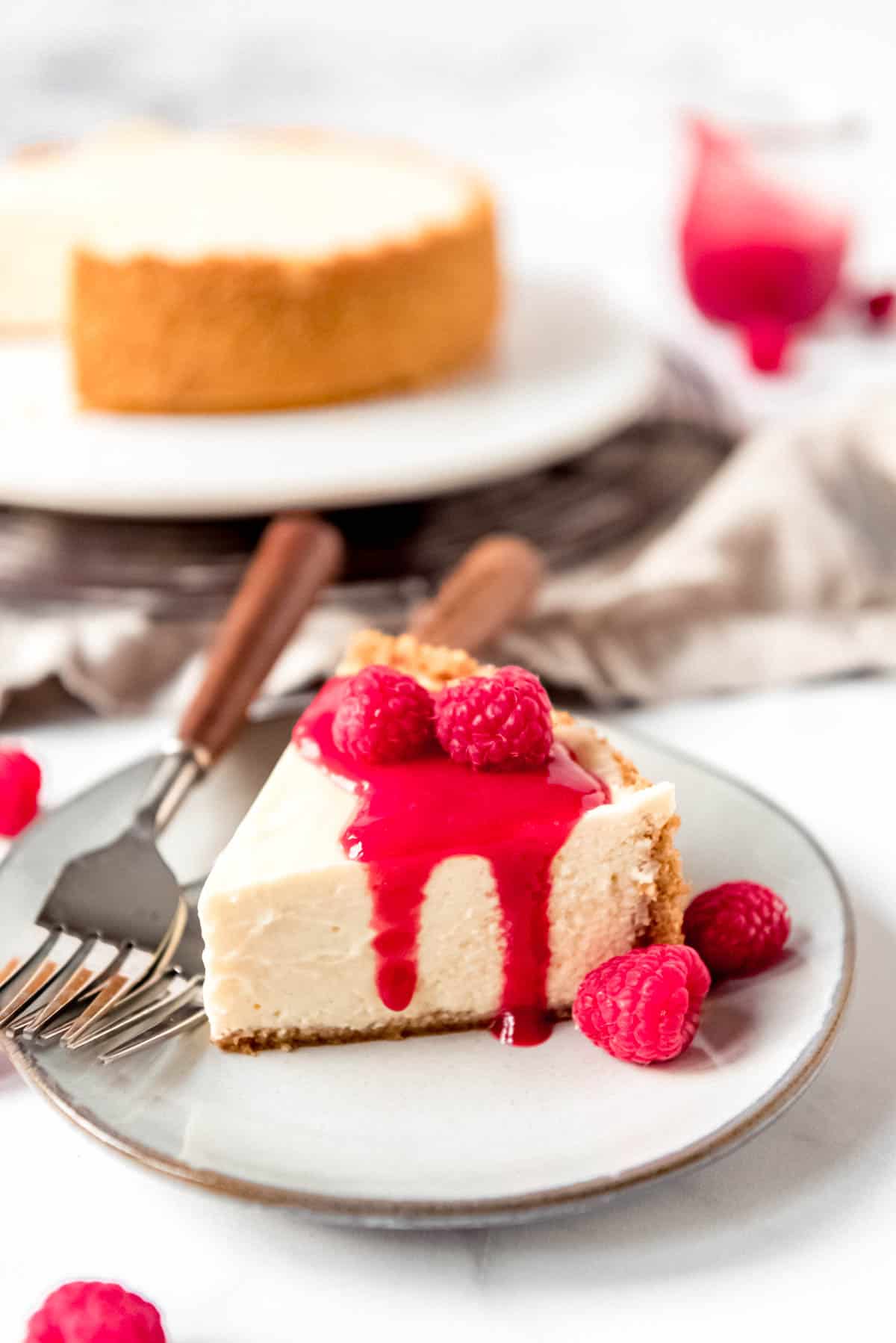A slice of cheesecake with raspberry sauce and raspberries on top.