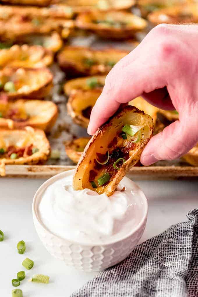 An image of a loaded potato skin being dipped into sour cream.