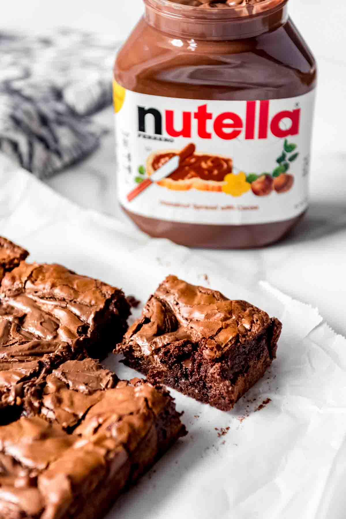 An image of homemade brownies in front of a Nutella jar.