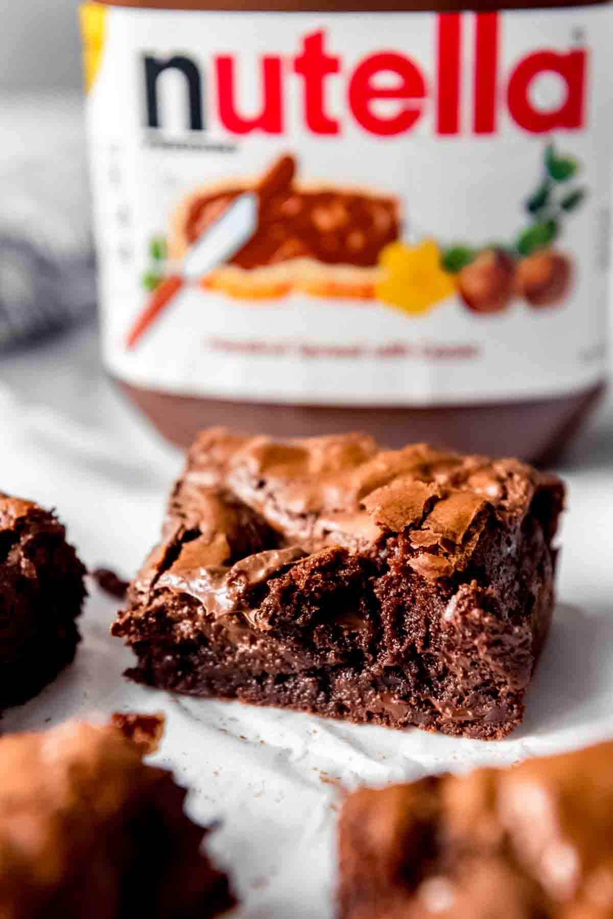 An image of a Nutella brownie in front of a jar of Nutella.