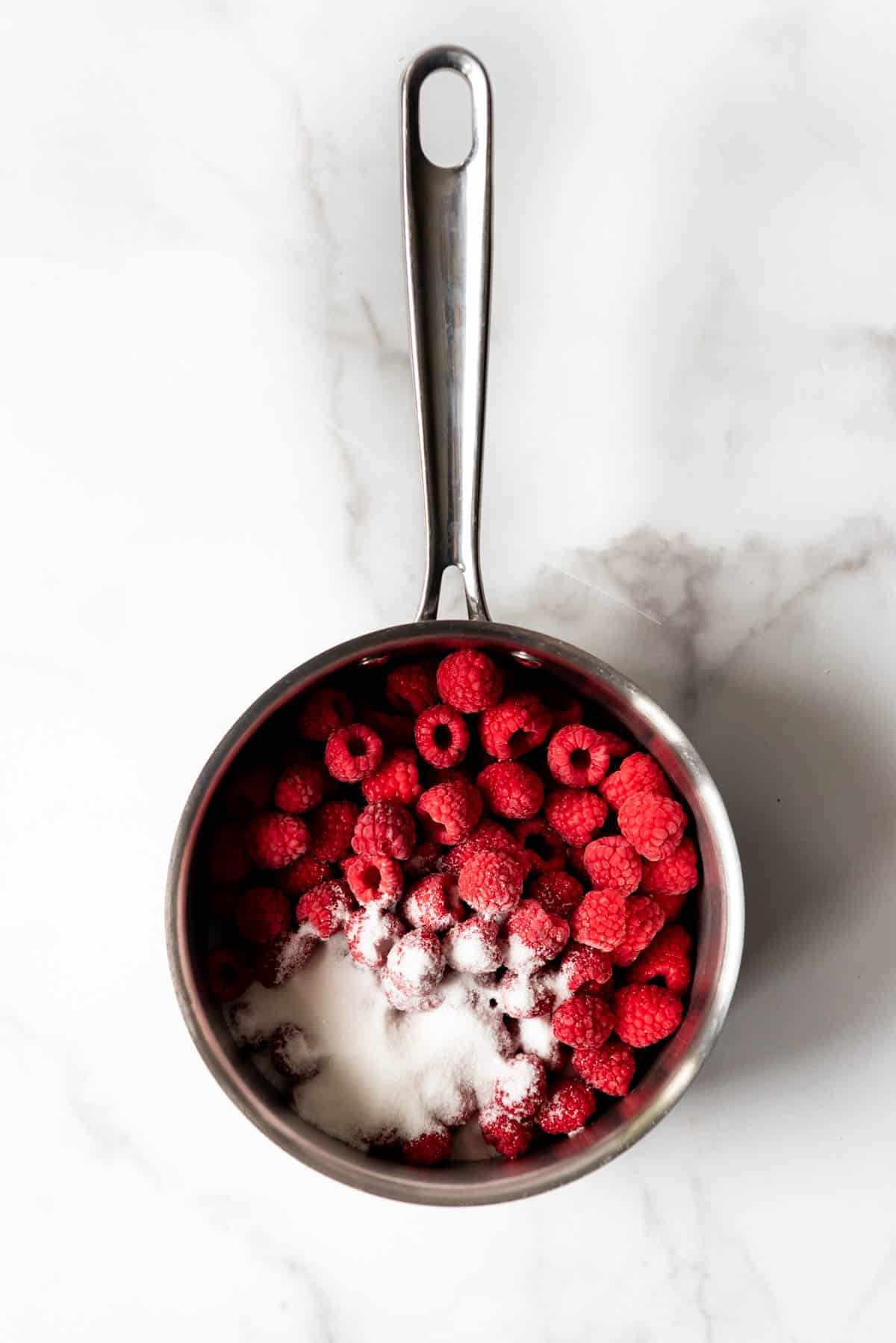 An image of raspberries and sugar in a saucepan.