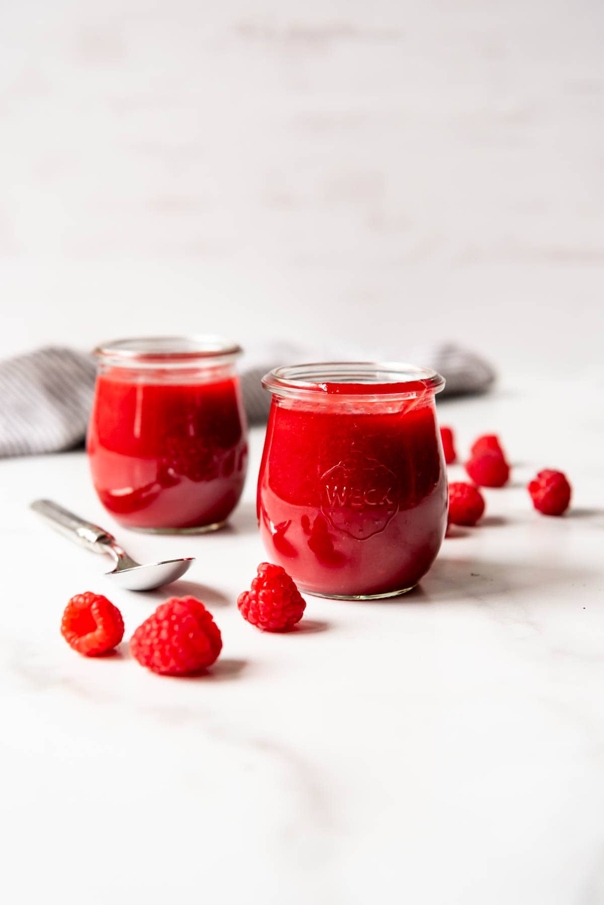 An image of two jars of homemade raspberry coulis sauce.