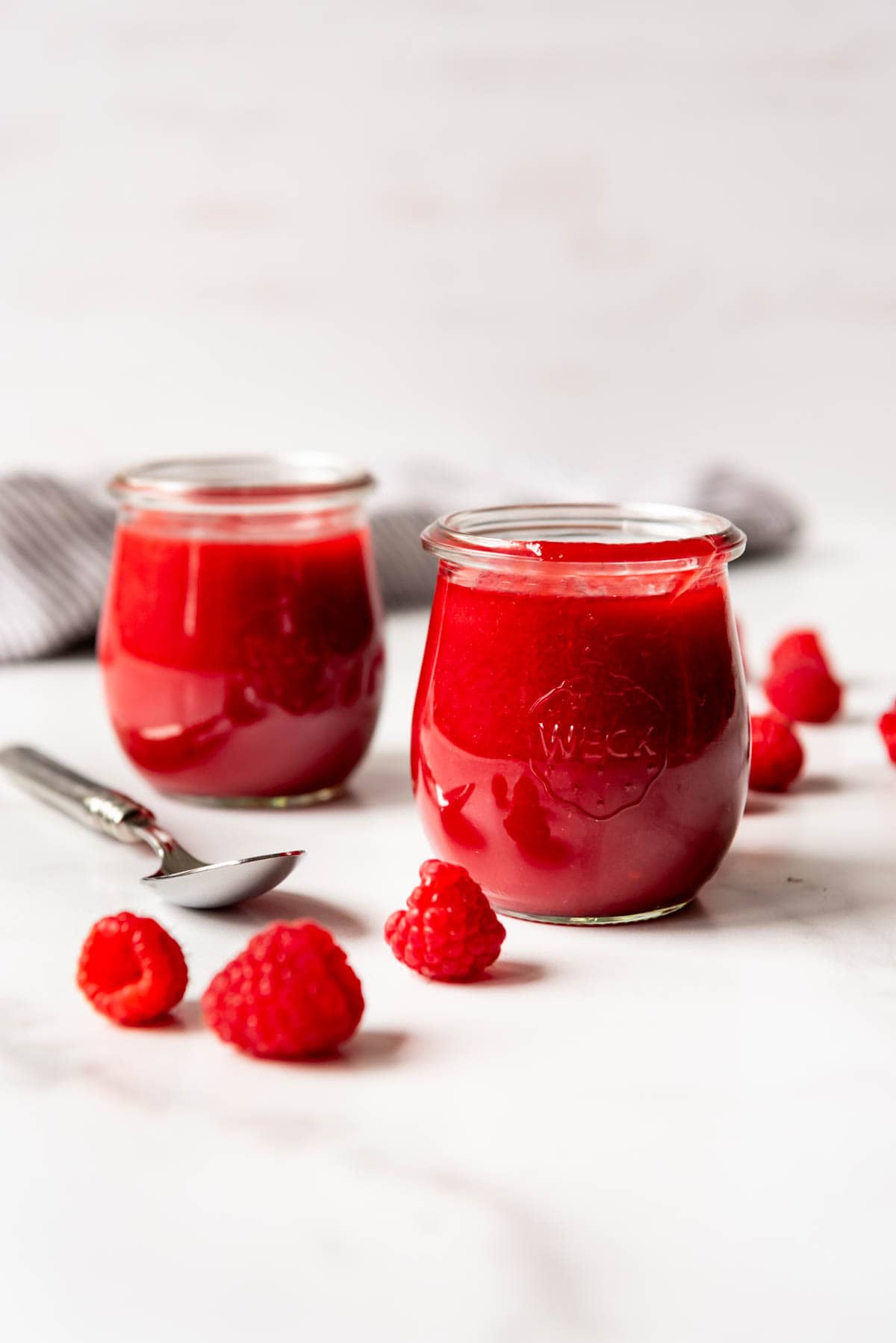 Two glass jars of raspberry sauce.