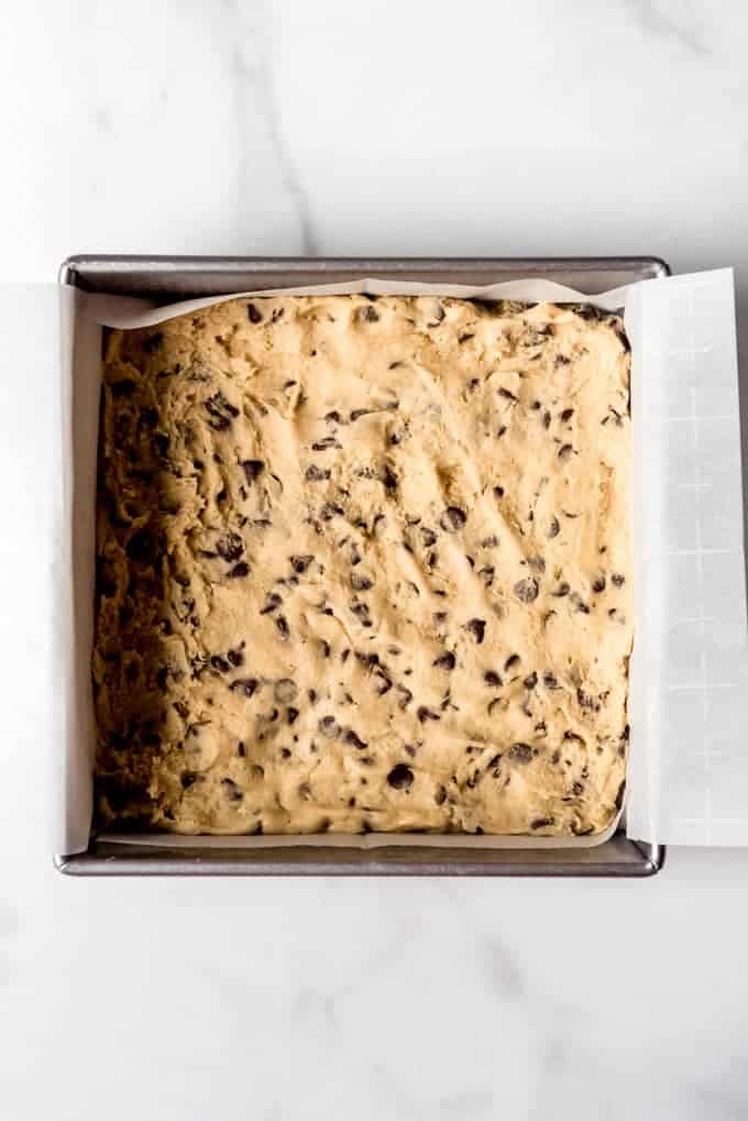 cookie dough pressed inside a parchment lined 8x8 baking dish