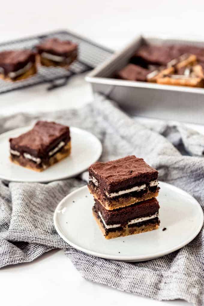 3-layer brownies with chocolate chip cookies on the bottom, Oreos in the middle, and brownies on top, on white plates.