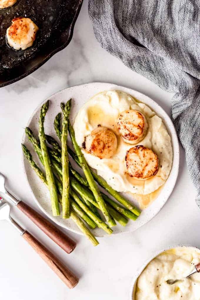 An image of a plate of scallops and asparagus.