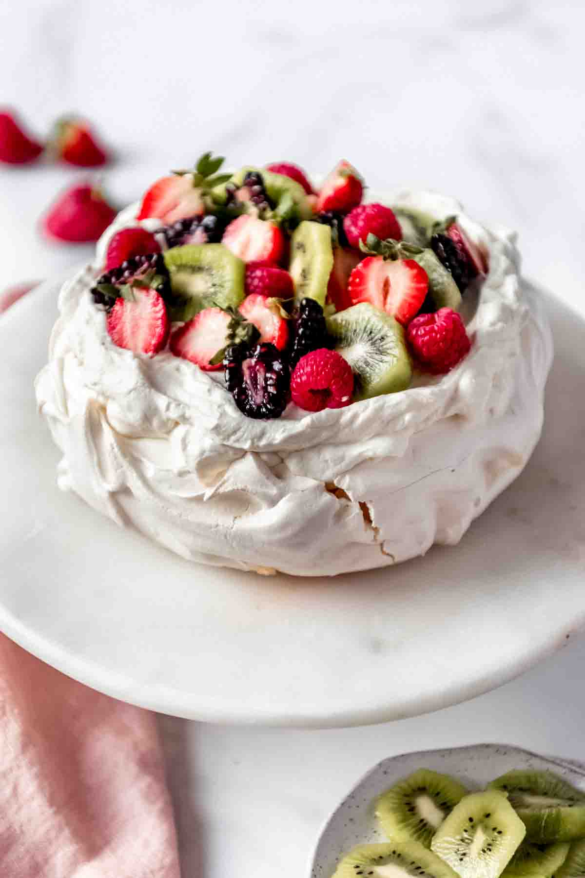 An image of a large pavlova dessert topped with fresh cream and fruit.