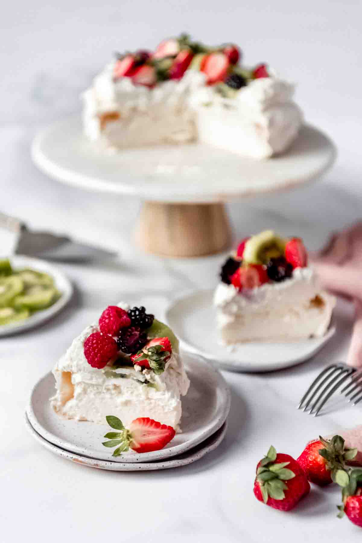 An image of a classic Australian dessert known as pavlova that has been sliced and served on plates with fresh fruit.