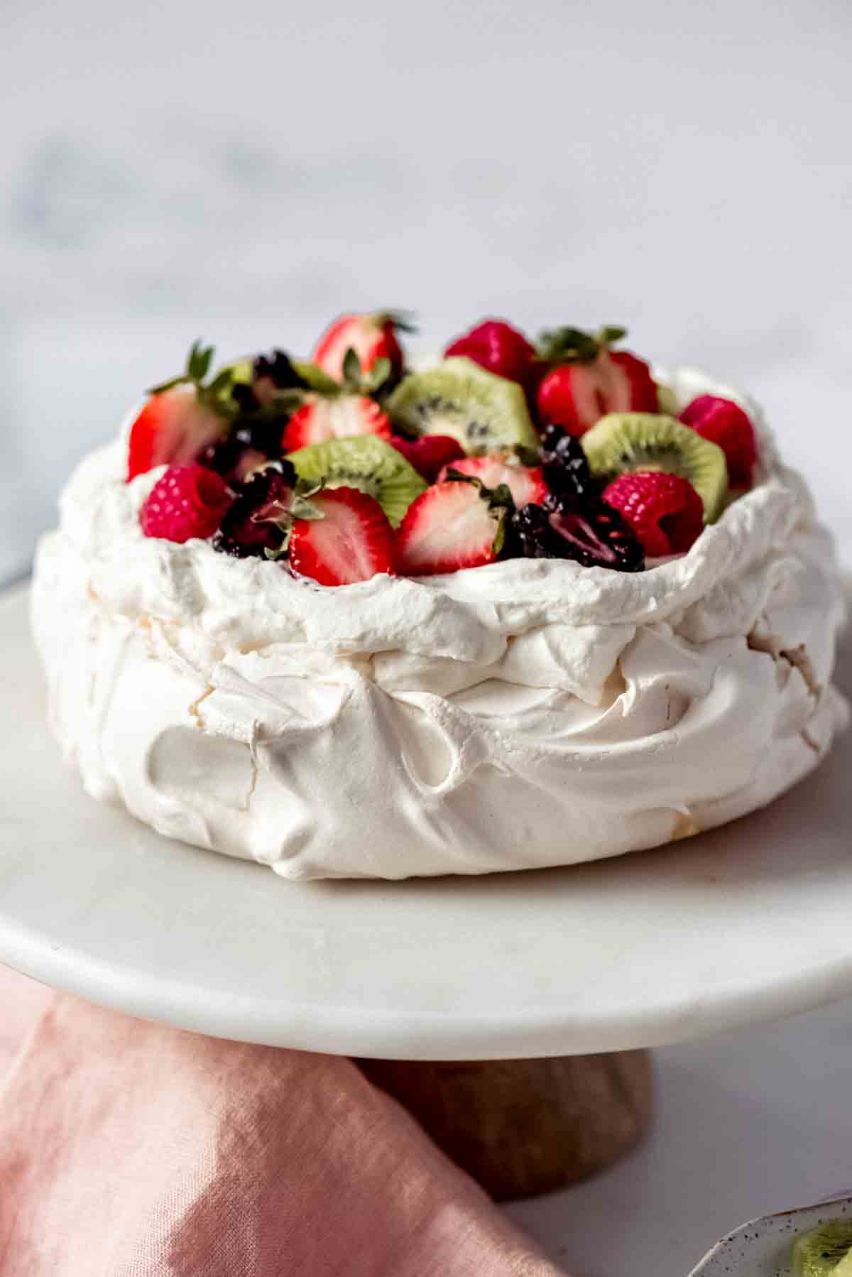 A pavlova topped with fruit and cream.