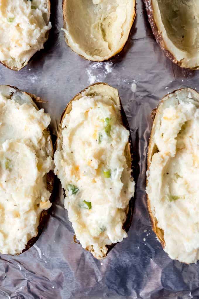 An image of potato skins filled with mashed potatoes, cheese, and green onions.