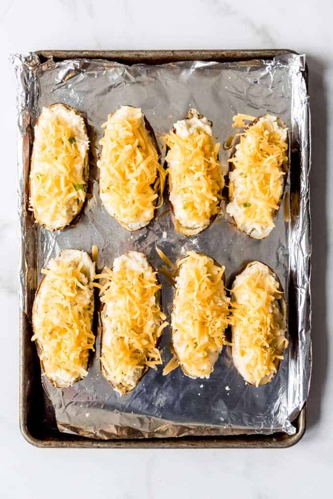 An image of twice baked potatoes covered in cheese and ready to go into the oven.