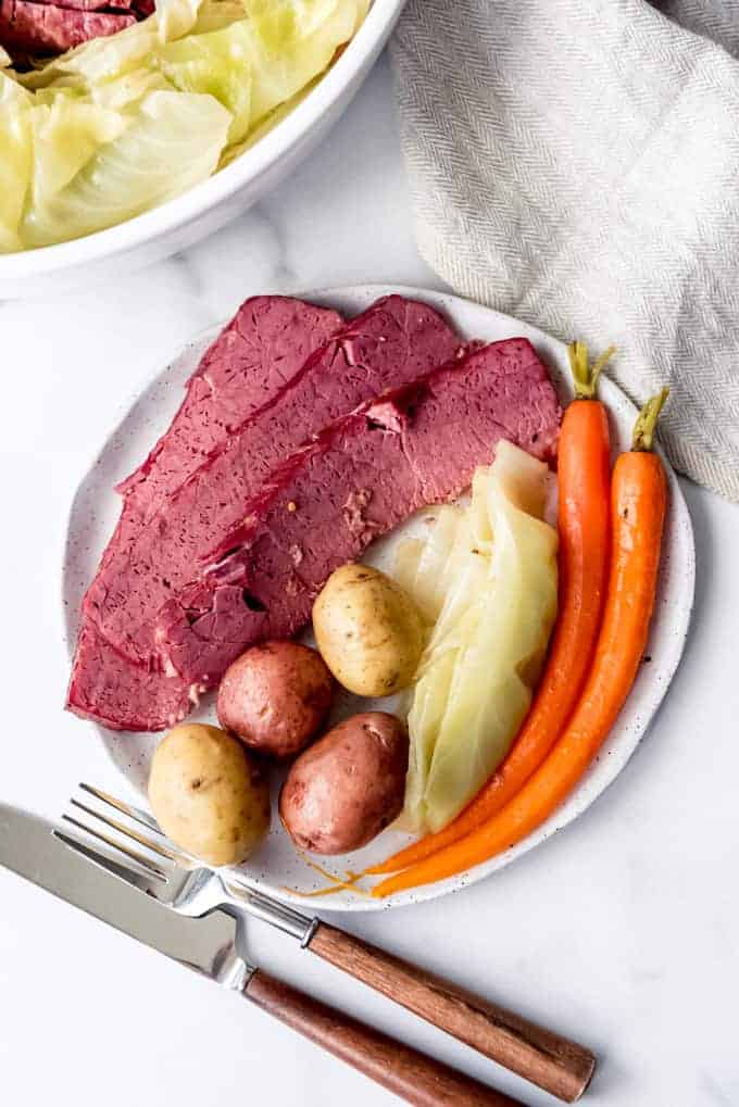 An image of a plate of slices of corned beef and cabbage with boiled potatoes and carrots.