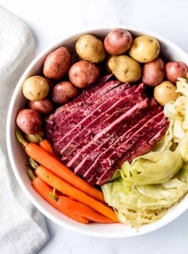 An image of a large plate of sliced corned beef and cabbage with potatoes and carrots.